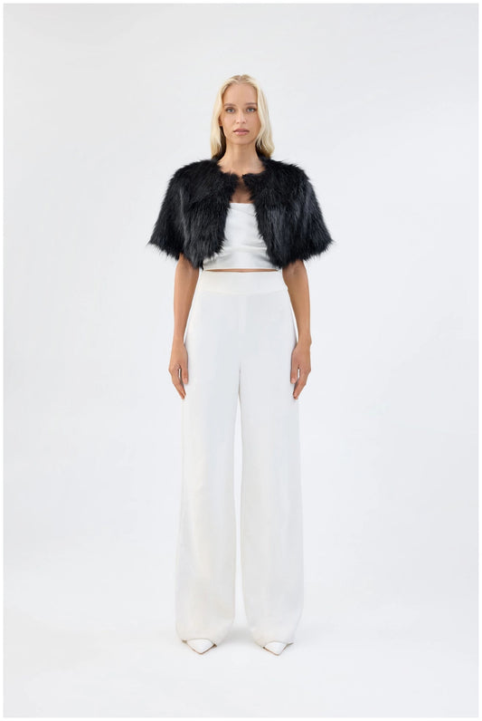 Model wearing Unreal Fur Love a Fur black faux fur bolero with cropped open-front silhouette and short sleeves, front view. 
