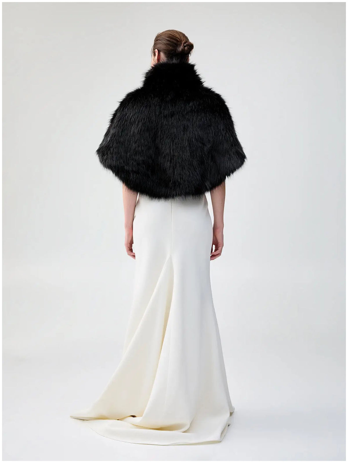 Back view of Unreal Fur Nord Cape in black showing the cropped cape silhouette, high collar and long-pile faux fur texture. 
