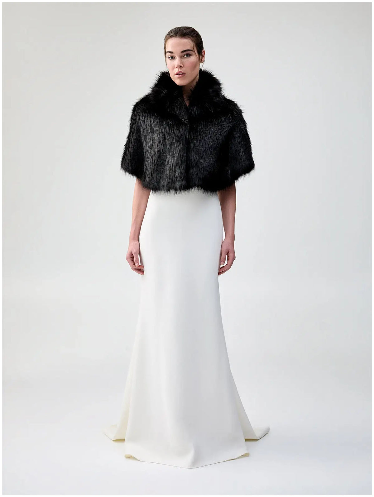 Front view of Unreal Fur Nord Cape in black showing the cropped cape silhouette, high collar and plush long-pile faux fur finish. 
