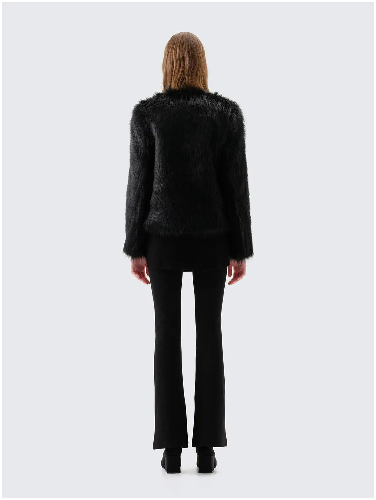 Back view of Unreal Fur Unreal Dream black faux fur jacket showing the straight hip-length silhouette, long sleeves and smooth plush texture. 
