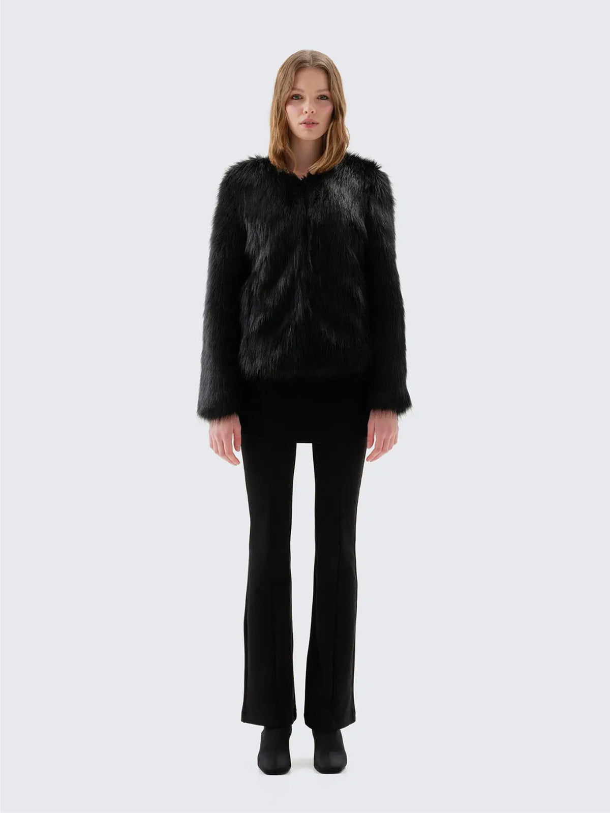 Back view of Unreal Fur Unreal Dream black faux fur jacket showing the straight hip-length silhouette, long sleeves and smooth plush texture. 
