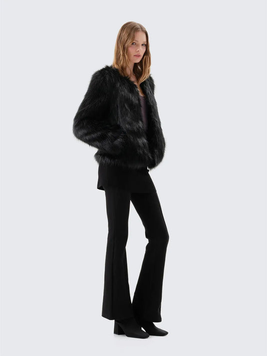 Side view of Unreal Fur Unreal Dream black faux fur jacket showing the relaxed fit, long sleeves and hip-length silhouette. 
