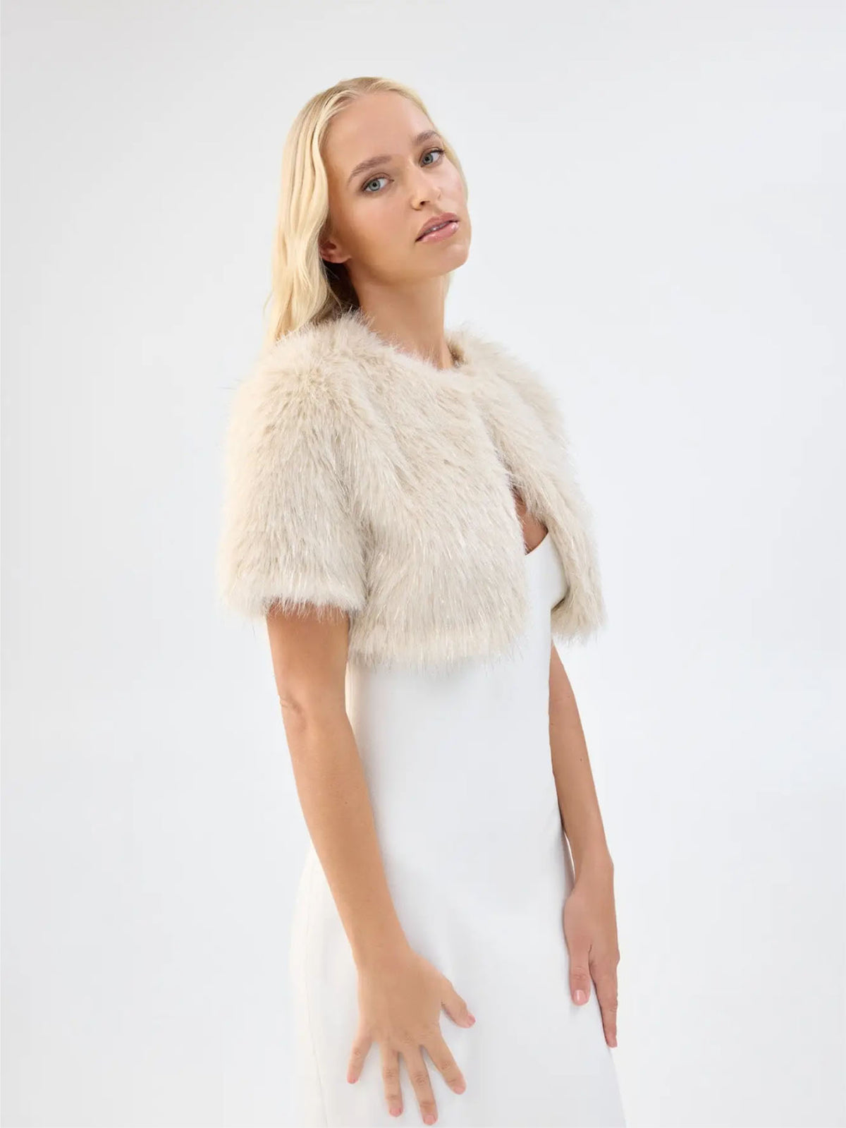 Side view of Unreal Fur Wings Bolero in caramel showing the cropped length, short sleeves and soft faux fur texture. 
