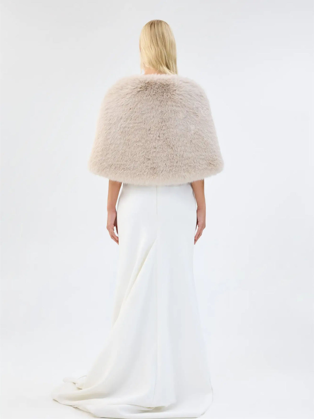 Back view of Unreal Fur Yasmine Wrap in almond faux fur styled over a white gown. 
