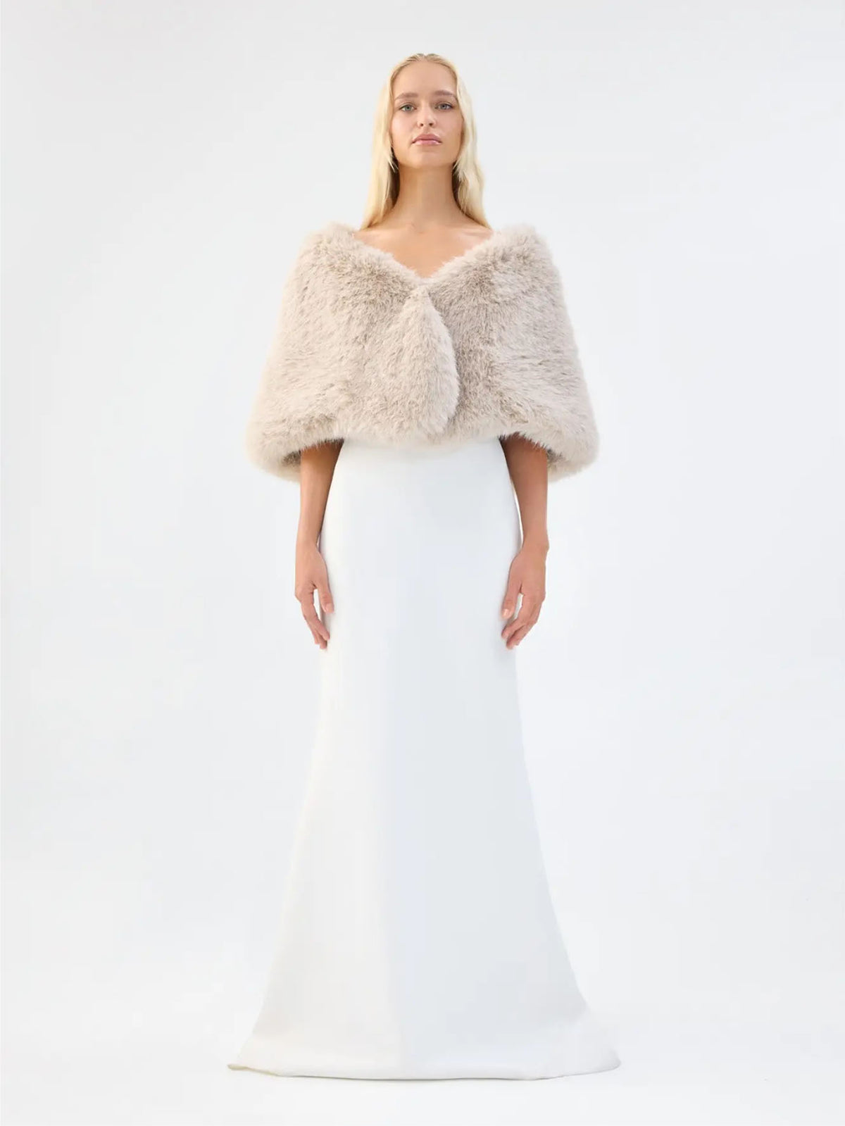 Front view of Unreal Fur Yasmine Wrap in almond faux fur styled over a white gown. 
