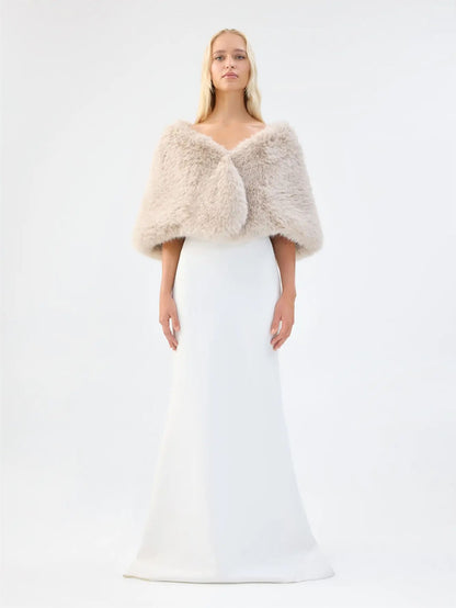 Front view of Unreal Fur Yasmine Wrap in almond faux fur styled over a white gown. 
