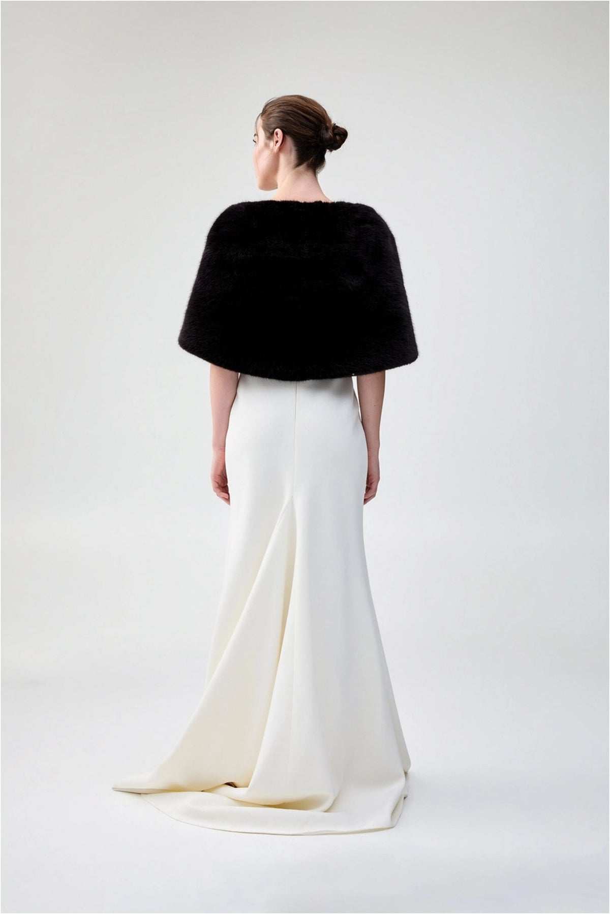 Back view of Unreal Fur Yasmine Wrap in black faux fur styled over a white gown. 
