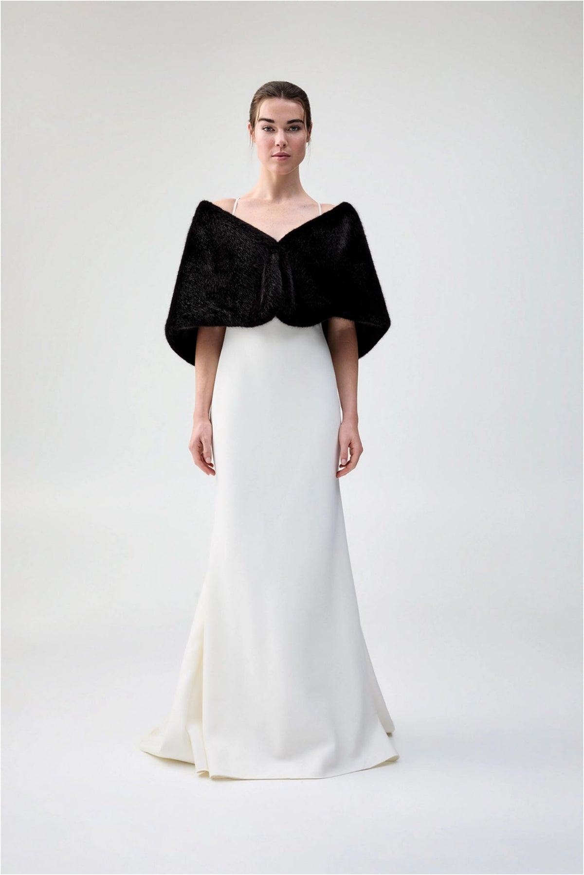 Front view of Unreal Fur Yasmine Wrap in black faux fur styled over a white gown. 
