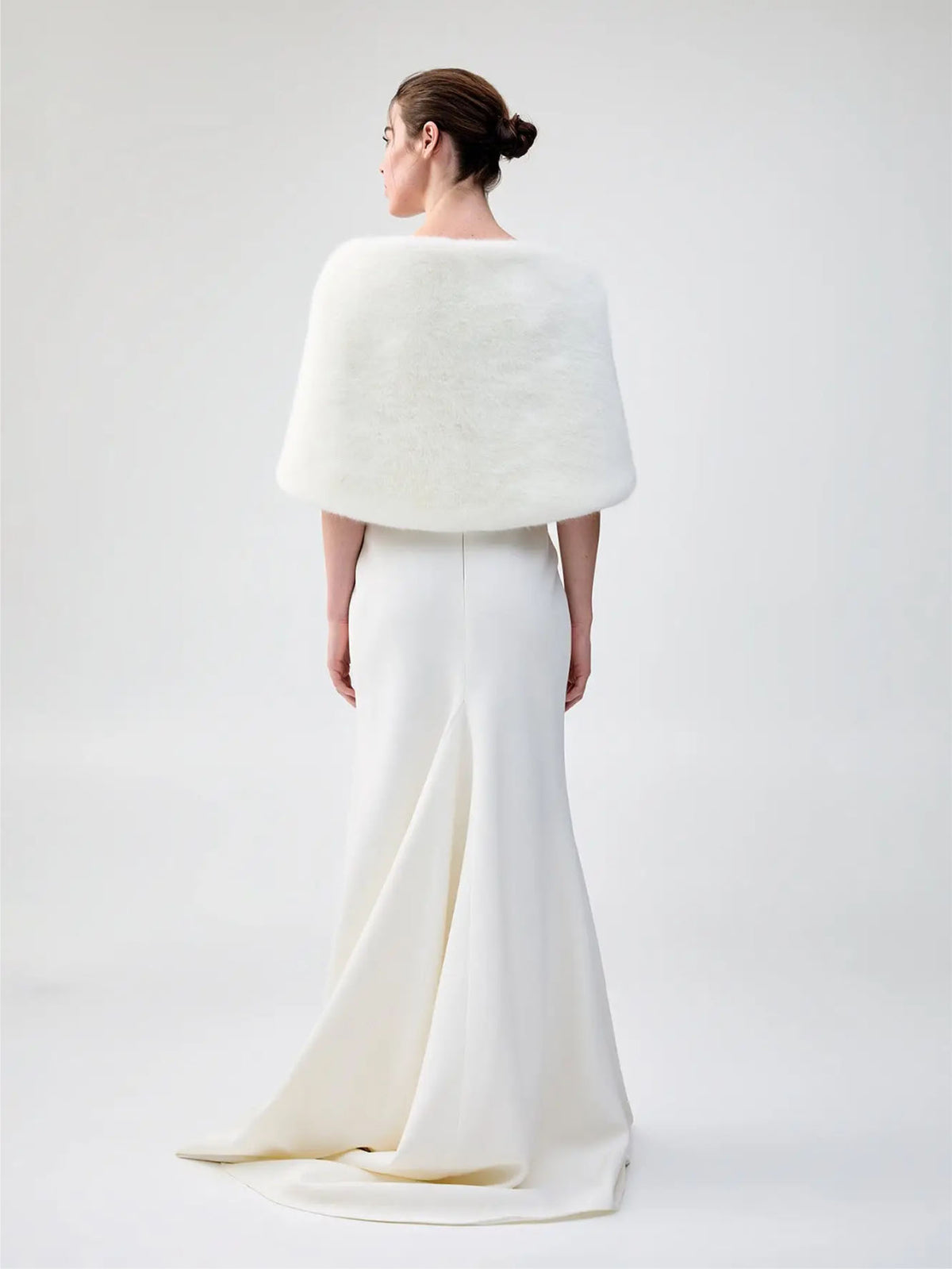 Back view of Unreal Fur Yasmine Wrap in white faux fur styled over a white gown. 
