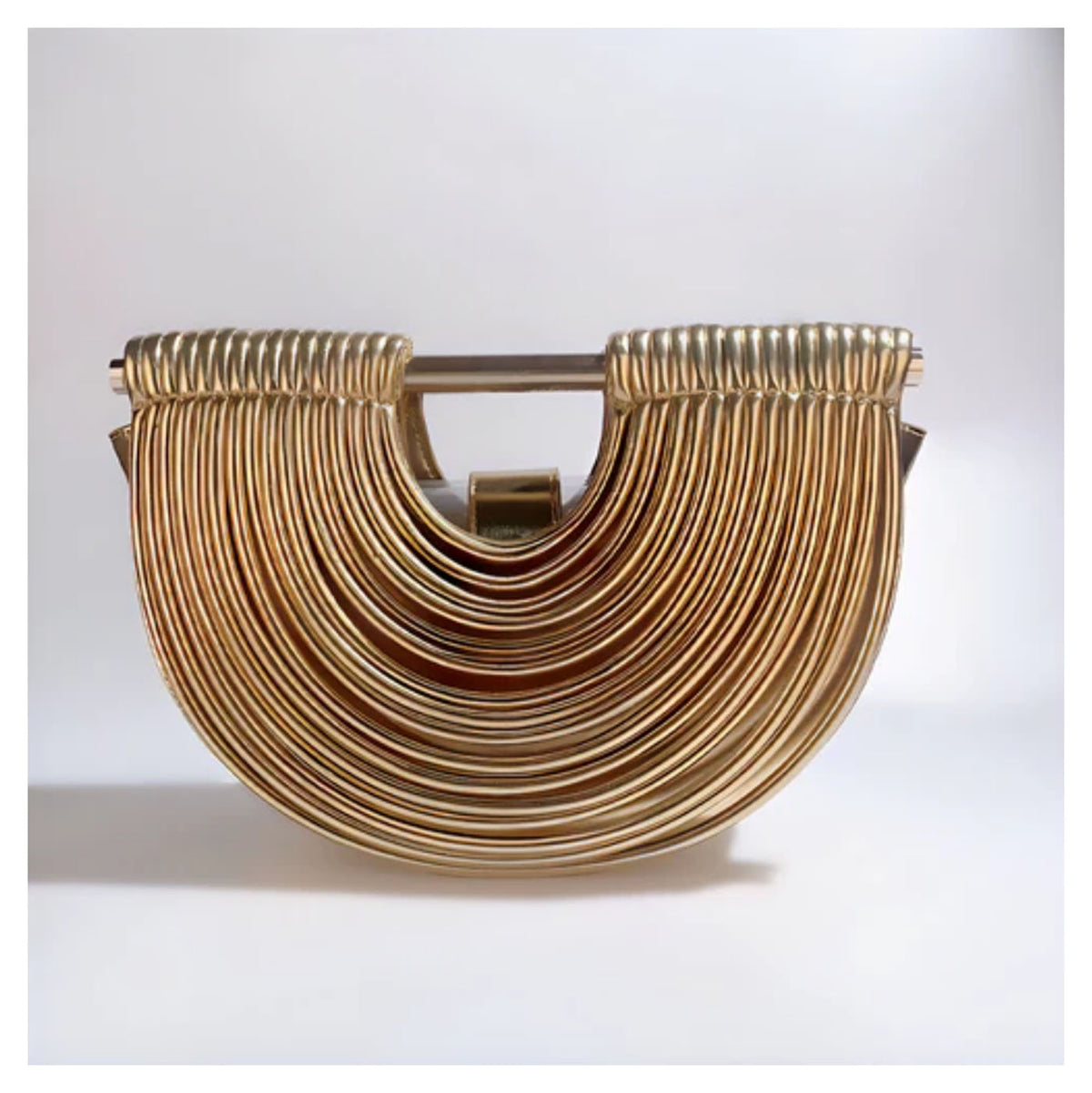 Verano Hill Amara gold handbag with sculptural ribbed semicircle design, front lifestyle view. 

