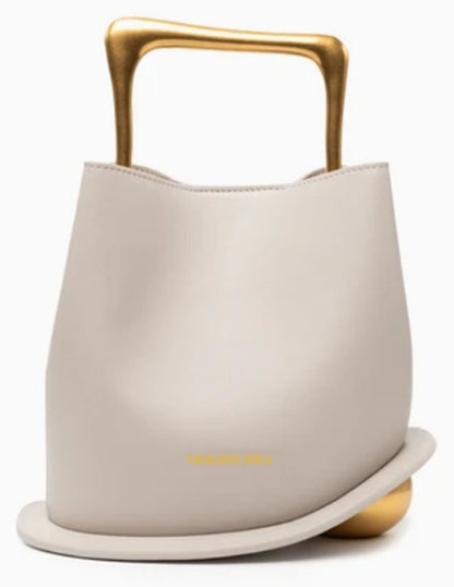 Verano Hill Vienna greige handbag with sculptural gold-tone top handle and curved base detail, front view. 
